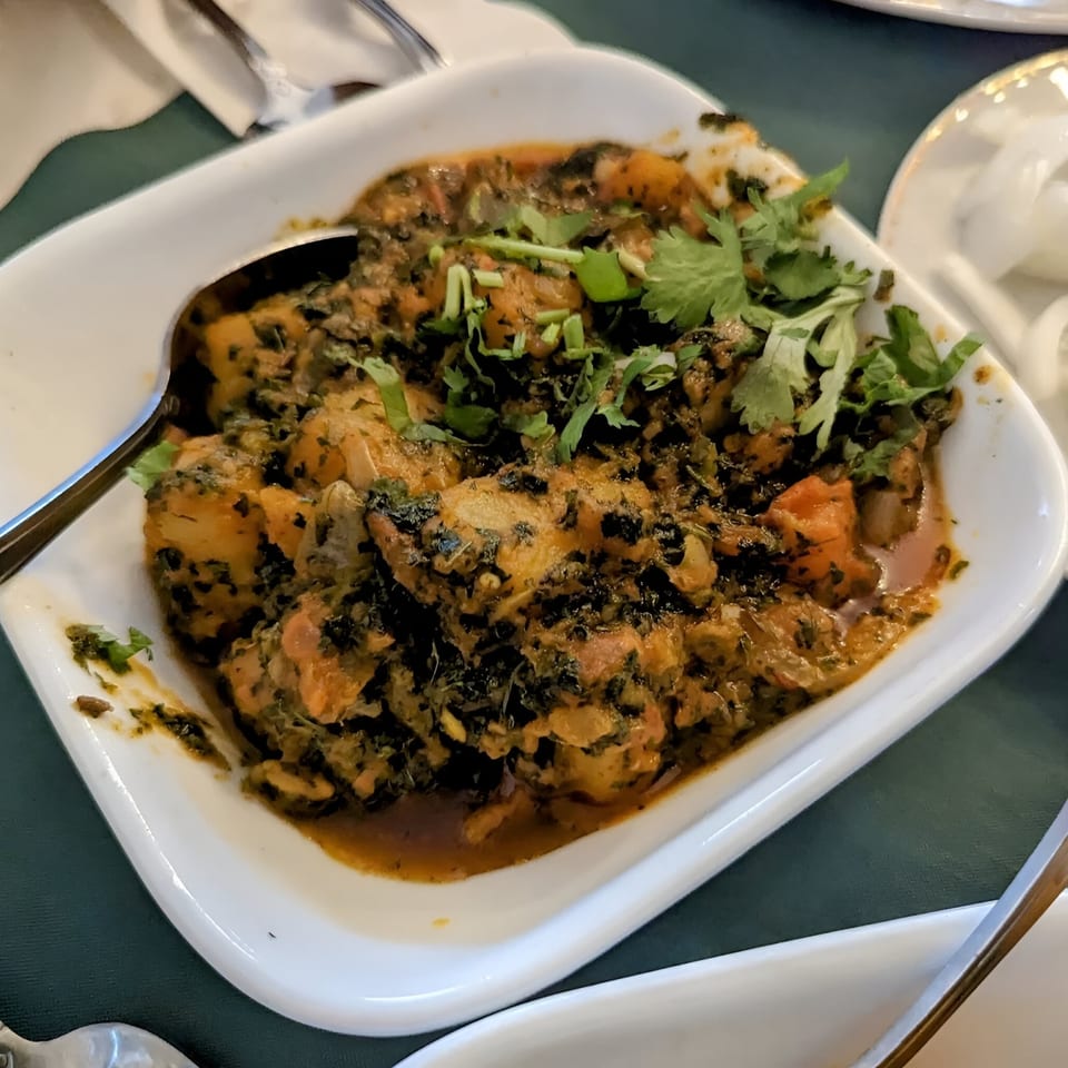 A white rectangular dish filled with a rich Indian curry, garnished with fresh cilantro.